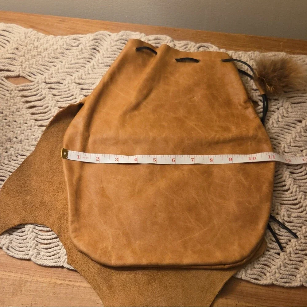 Handcrafted tan leather drawstring pouch featuring a soft fur pom-pom